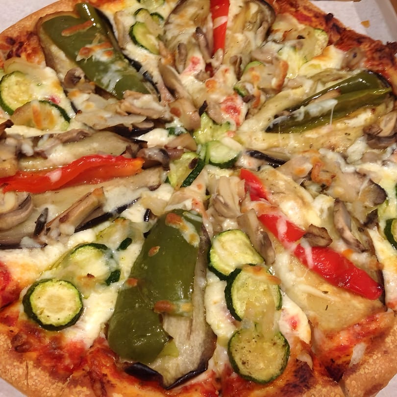 A close-up of a Townies Feel Good Food pizza, topped with zucchini, bell peppers, and mushrooms.